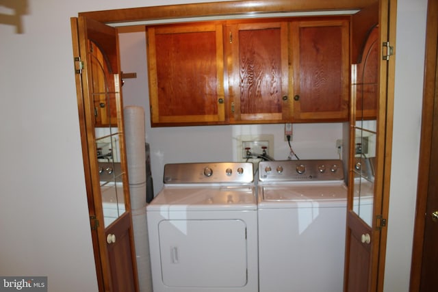 laundry room featuring washing machine and clothes dryer and cabinets