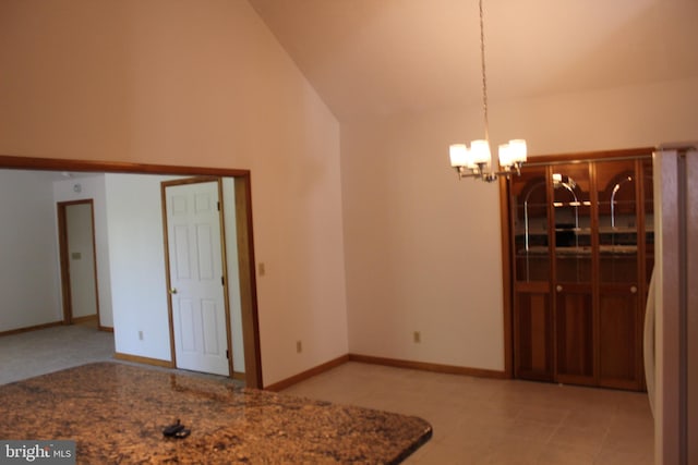 unfurnished dining area with a notable chandelier, lofted ceiling, and light tile patterned floors