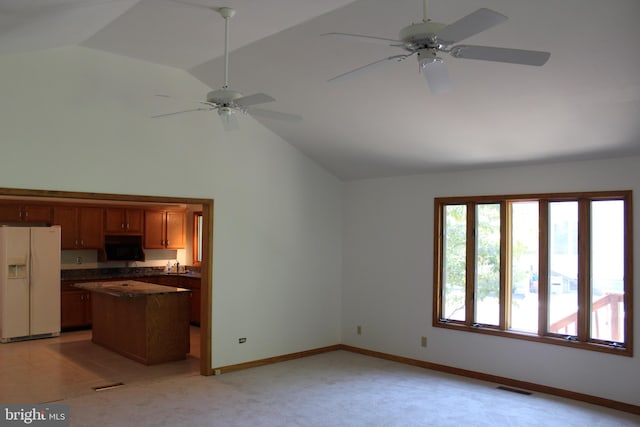 kitchen with white fridge with ice dispenser, ceiling fan, lofted ceiling, and light colored carpet