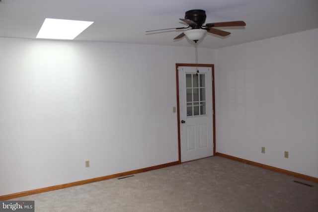 carpeted empty room with ceiling fan and a skylight