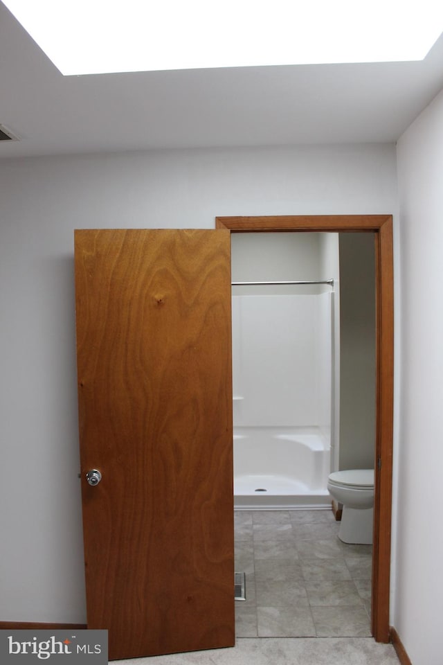 bathroom with toilet, walk in shower, and tile patterned floors