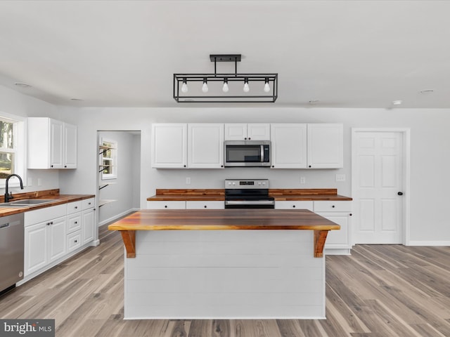 kitchen featuring stainless steel appliances, sink, butcher block counters, and light hardwood / wood-style floors