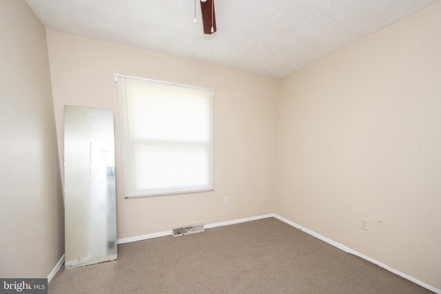 empty room with ceiling fan, carpet flooring, and a textured ceiling