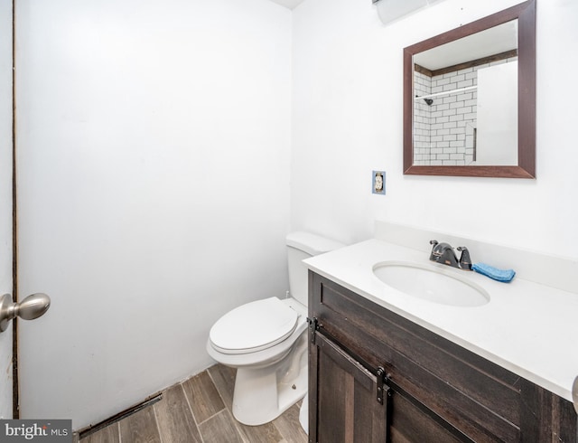 bathroom with toilet, hardwood / wood-style floors, and vanity