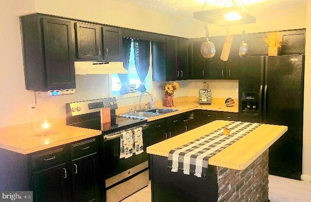 kitchen with sink, wooden counters, decorative light fixtures, extractor fan, and black appliances