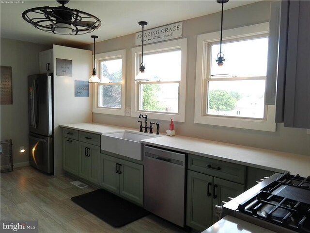 kitchen with stainless steel dishwasher, refrigerator, plenty of natural light, hardwood / wood-style flooring, and hanging light fixtures