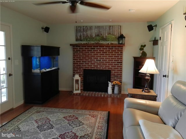 living area featuring a ceiling fan, a fireplace, baseboards, and wood finished floors