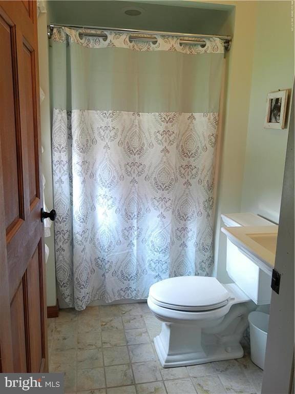 bathroom with toilet, a shower with shower curtain, vanity, and tile patterned floors