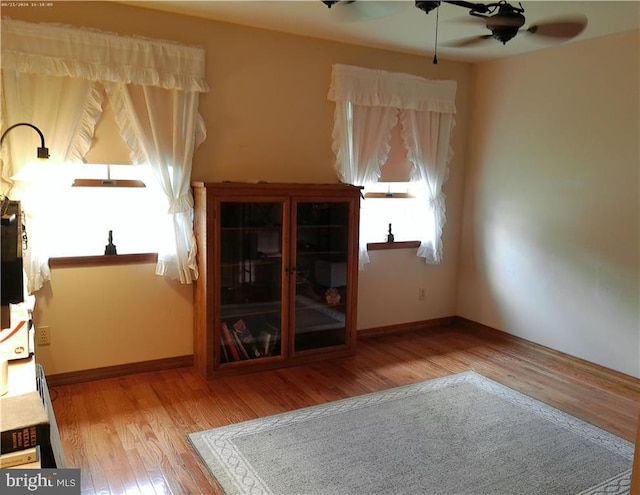 unfurnished living room featuring light wood-type flooring, baseboards, and a ceiling fan