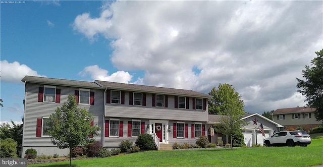 colonial home featuring a garage and a front lawn