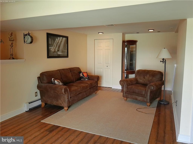 living room with dark hardwood / wood-style flooring and a baseboard heating unit