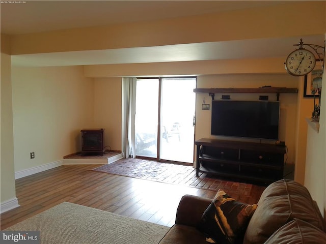 living room featuring wood finished floors, a wood stove, and baseboards