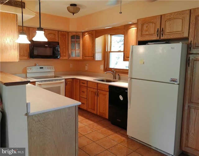 kitchen featuring pendant lighting, light countertops, glass insert cabinets, a sink, and black appliances