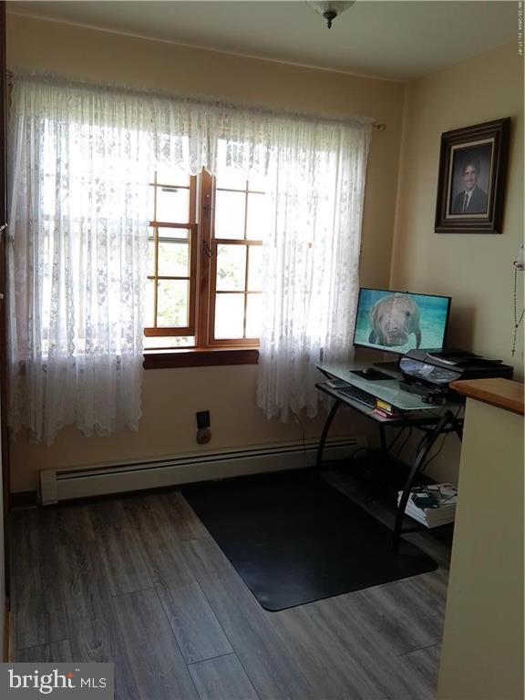 office space with a baseboard heating unit and wood-type flooring