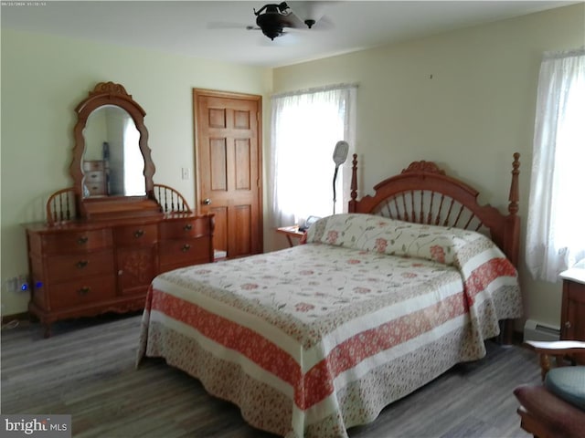 bedroom with ceiling fan, a baseboard heating unit, and wood-type flooring