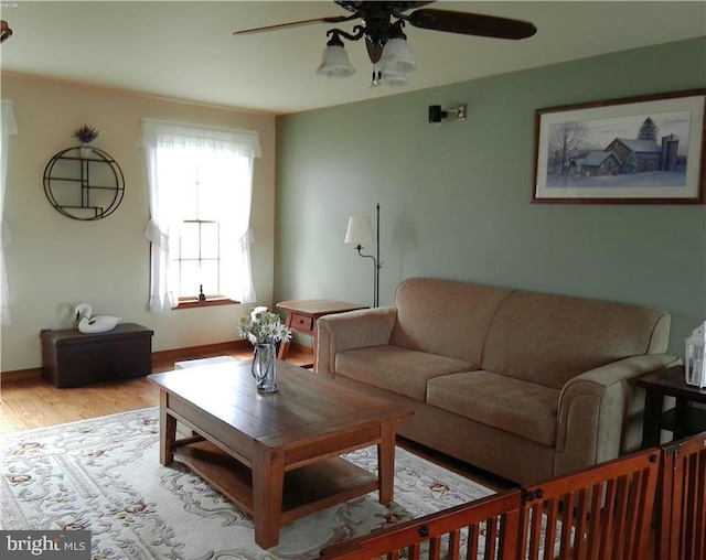 living area with light wood-style flooring, baseboards, and a ceiling fan