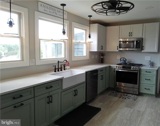 kitchen with white cabinets, appliances with stainless steel finishes, a sink, light countertops, and a wealth of natural light