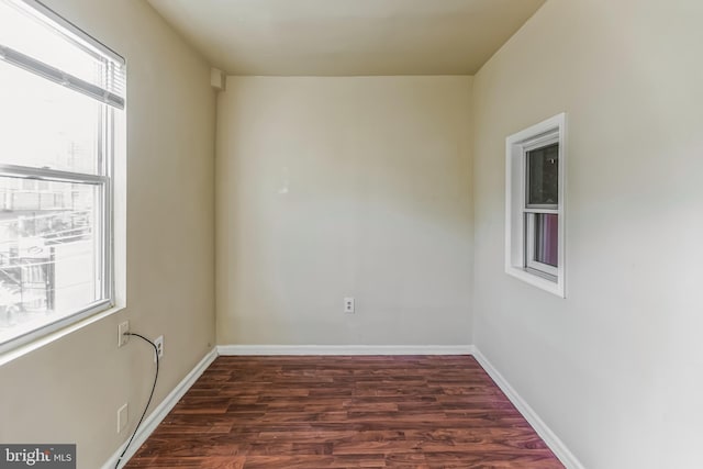 unfurnished room featuring baseboards and dark wood finished floors