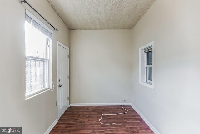 empty room featuring baseboards and dark wood-type flooring