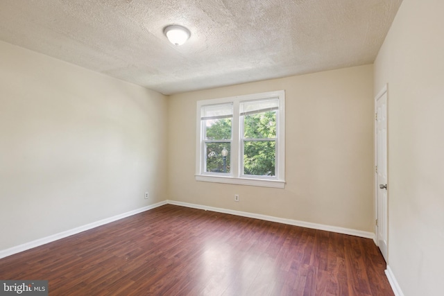 spare room with dark wood-style floors, baseboards, and a textured ceiling