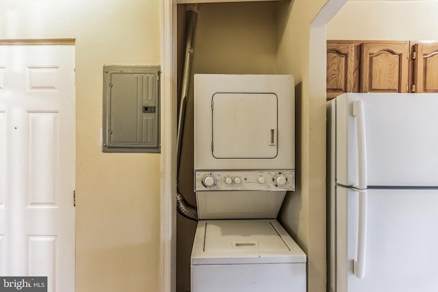 clothes washing area with stacked washer / dryer and electric panel