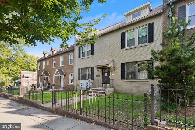 view of front of property featuring a fenced front yard, brick siding, and a front lawn