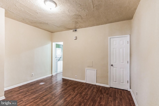 empty room featuring a textured ceiling, dark wood-type flooring, visible vents, and baseboards