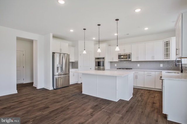 kitchen with backsplash, dark hardwood / wood-style floors, a kitchen island, appliances with stainless steel finishes, and sink