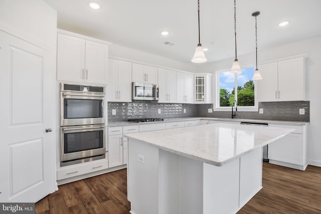 kitchen featuring decorative backsplash, stainless steel appliances, dark wood-type flooring, and white cabinets