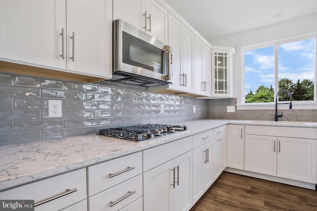 kitchen with dark hardwood / wood-style flooring, tasteful backsplash, white cabinets, sink, and stainless steel appliances