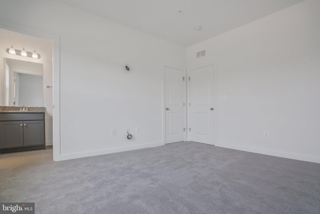 unfurnished bedroom featuring light colored carpet, connected bathroom, and sink