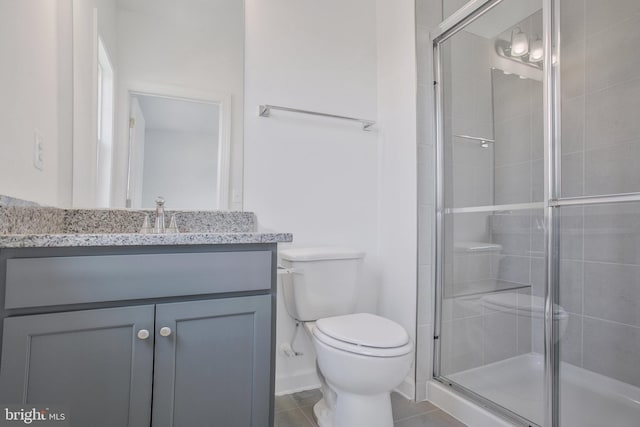 bathroom featuring tile patterned floors, a shower with door, vanity, and toilet