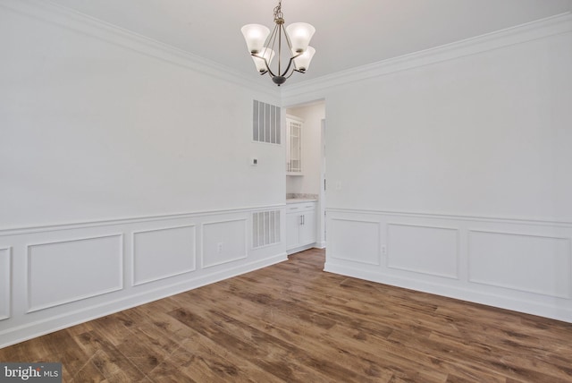 unfurnished dining area featuring hardwood / wood-style floors, ornamental molding, and a chandelier