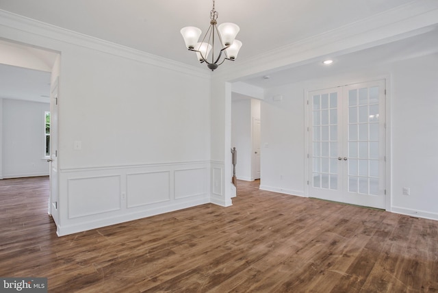 spare room with crown molding, a chandelier, hardwood / wood-style flooring, and french doors