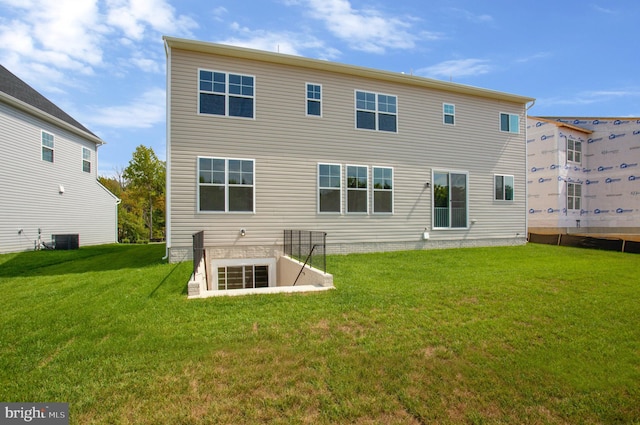 rear view of house with central air condition unit and a lawn