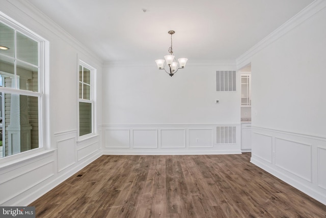 unfurnished dining area with dark hardwood / wood-style floors, an inviting chandelier, and ornamental molding