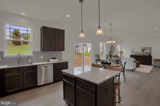 kitchen with dishwasher, light stone counters, a sink, and decorative light fixtures