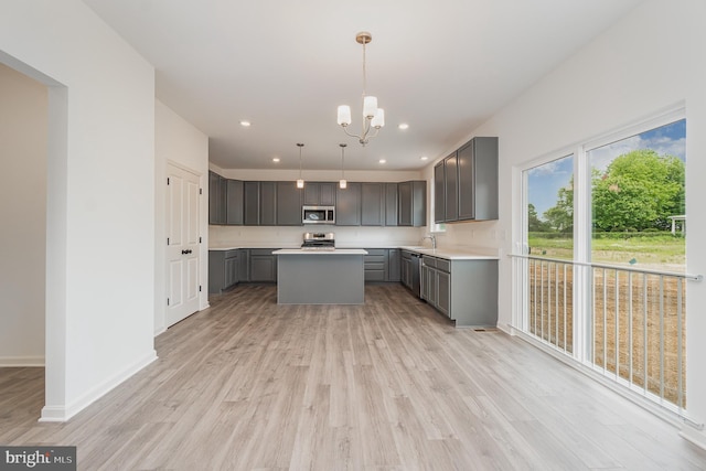 kitchen with a center island, range, light hardwood / wood-style floors, gray cabinetry, and hanging light fixtures