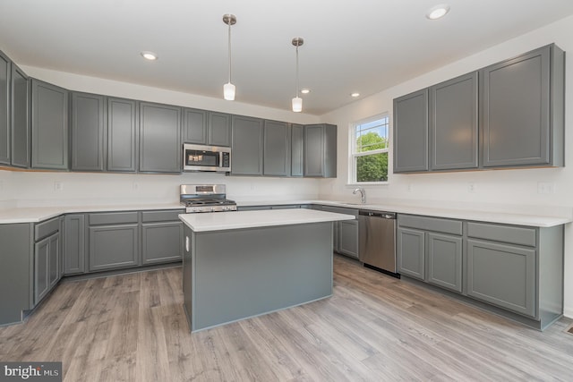 kitchen featuring stainless steel appliances, light hardwood / wood-style floors, sink, a kitchen island, and gray cabinets