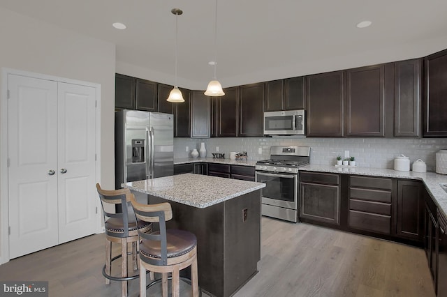 kitchen with appliances with stainless steel finishes, a breakfast bar, hanging light fixtures, and dark brown cabinetry