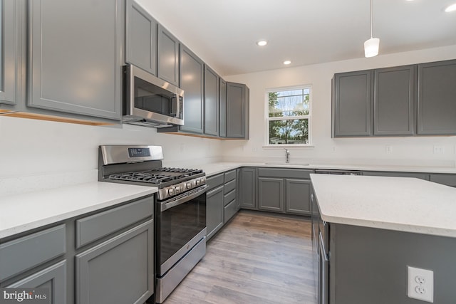 kitchen featuring light hardwood / wood-style flooring, gray cabinets, appliances with stainless steel finishes, light stone countertops, and sink