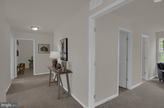 hallway with light carpet, baseboards, and visible vents