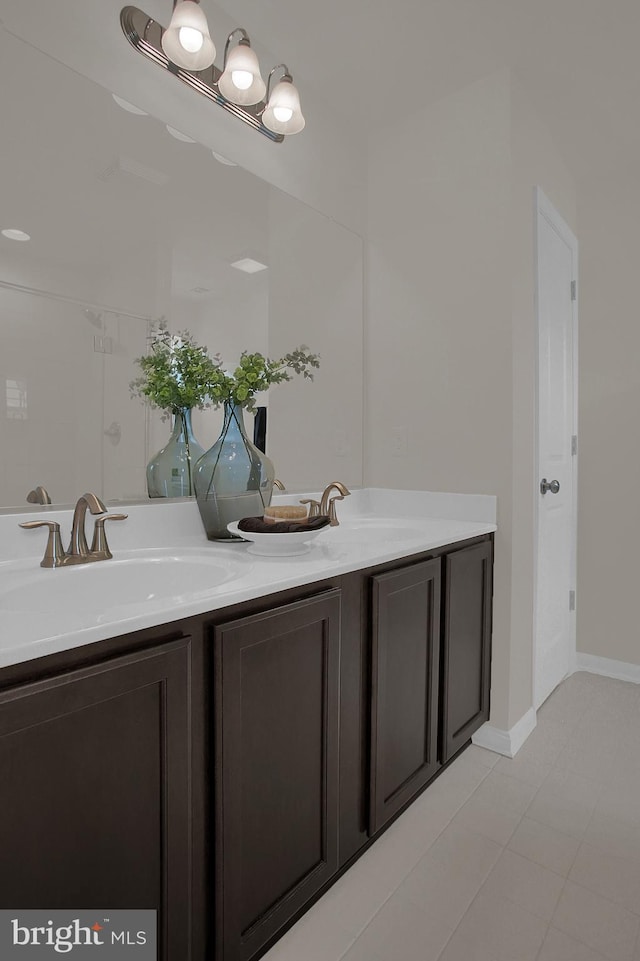 bathroom featuring double vanity, a sink, and baseboards