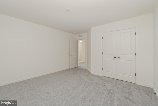 unfurnished bedroom featuring light colored carpet and a closet