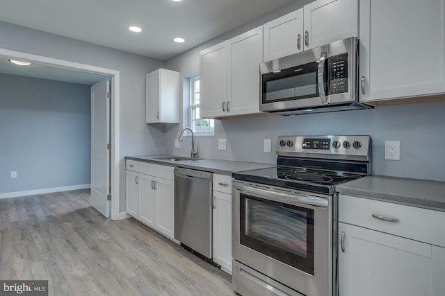 kitchen featuring appliances with stainless steel finishes, light hardwood / wood-style flooring, white cabinets, and sink