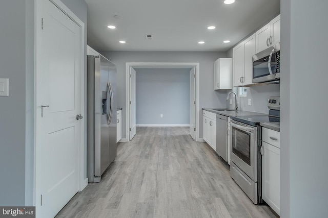 kitchen featuring light wood-type flooring, sink, stainless steel appliances, and white cabinets