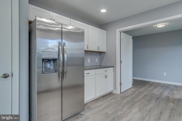 kitchen with light hardwood / wood-style floors, stainless steel refrigerator with ice dispenser, and white cabinetry