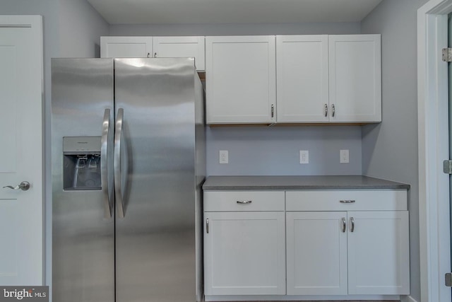 kitchen featuring stainless steel fridge with ice dispenser and white cabinetry