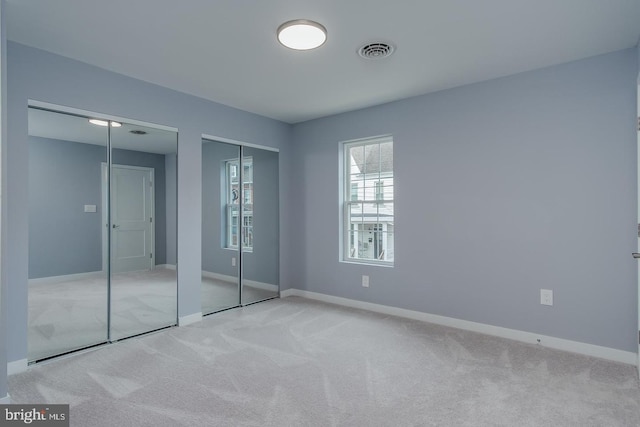 unfurnished bedroom featuring carpet floors and multiple closets