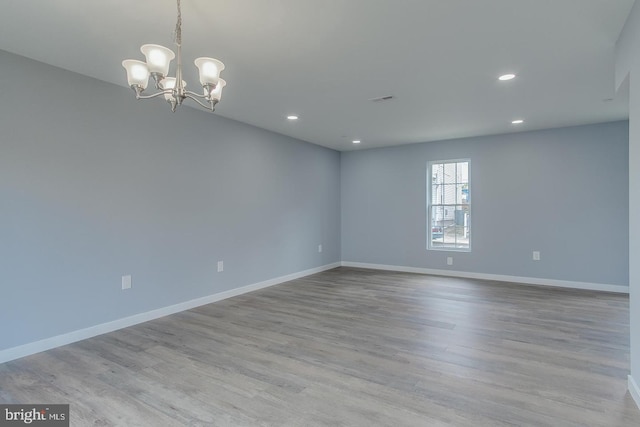 empty room with light hardwood / wood-style floors and an inviting chandelier